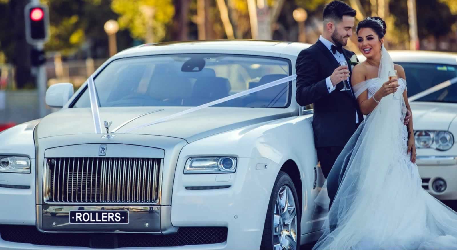 White Rolls -Royce Ghost wedding with bride & groom sipping champagne